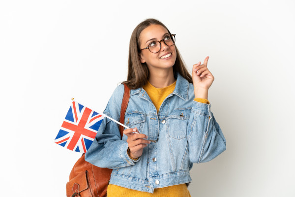 Young hispanic woman holding an United Kingdom flag over isolated white background pointing up a great idea