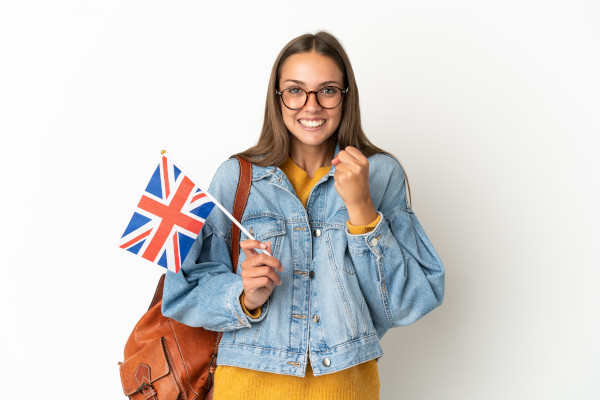 Young hispanic woman holding an United Kingdom flag over isolated white background celebrating a victory in winner position