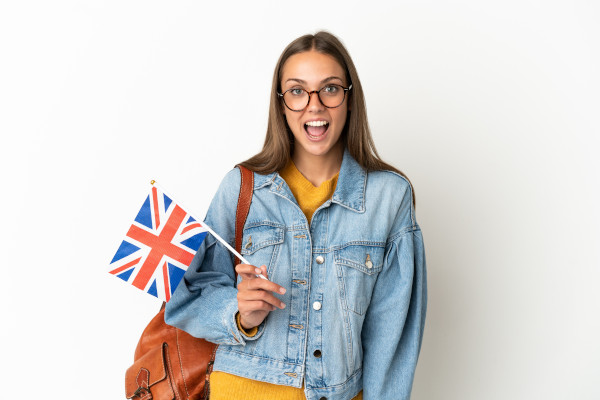 Young hispanic woman holding an United Kingdom flag over isolated white background with surprise facial expression